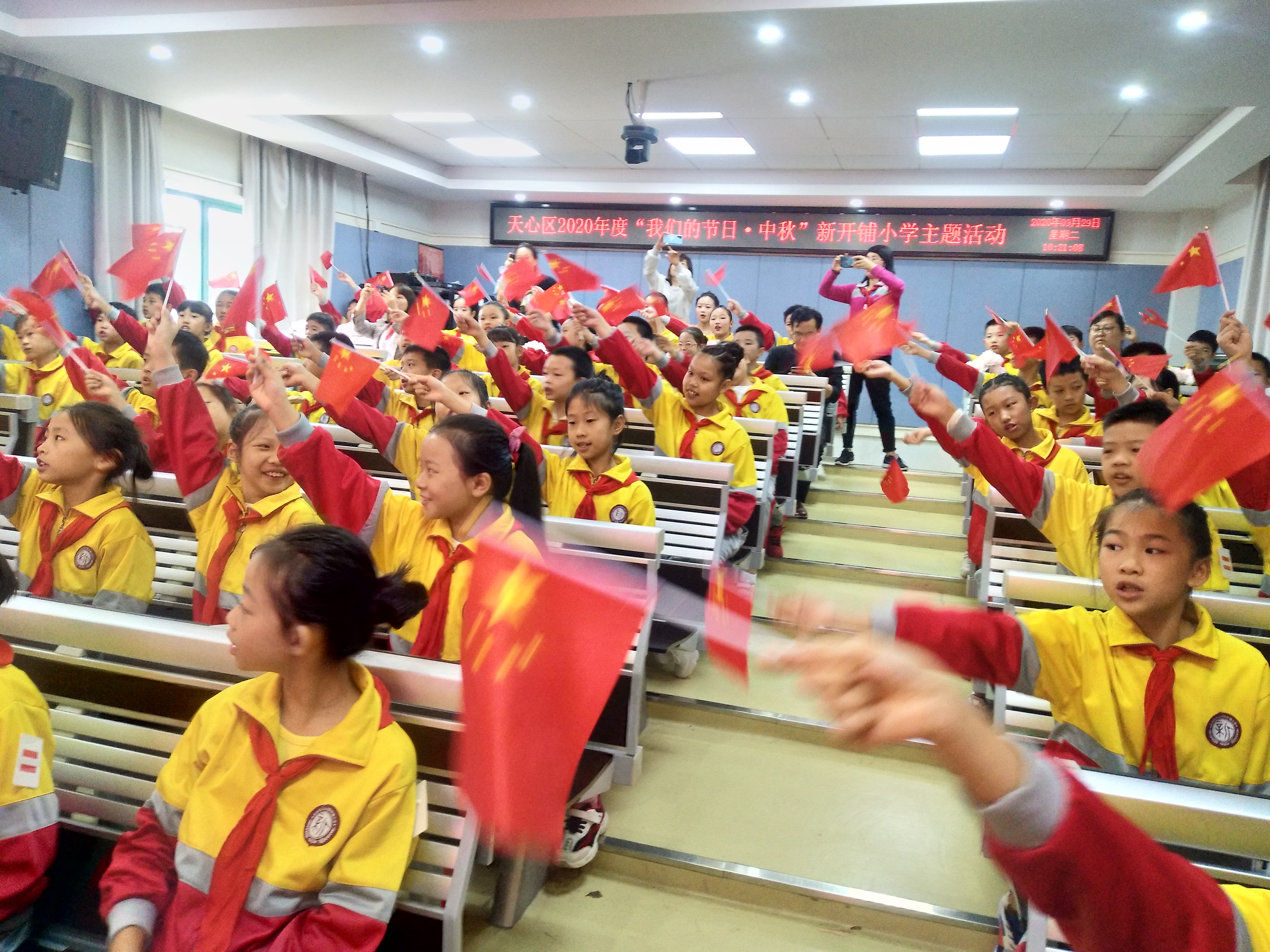 同学们挥舞着红旗，唱响《我和我的祖国》。
