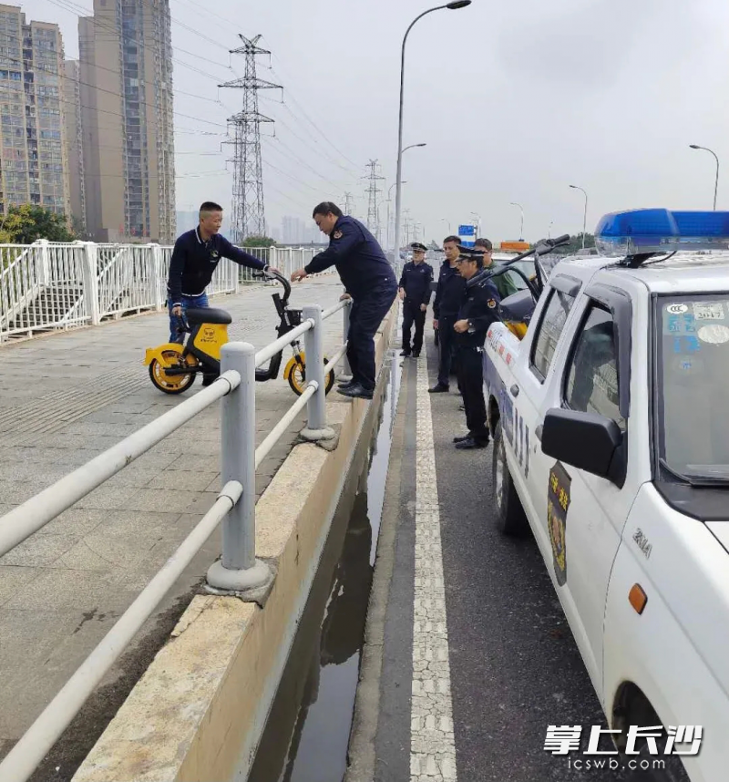 执法人员在清理丢在桥上的共享电摩。芙蓉区供图