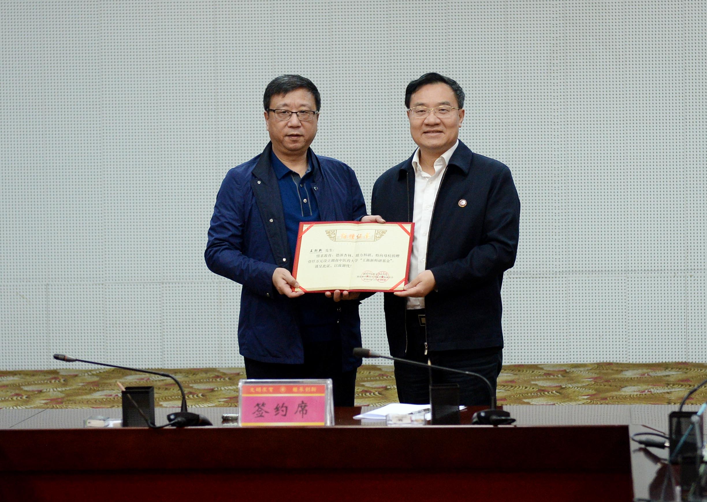 湖南中医药大学党委书记秦裕辉（右）为79级校友王衡新颁发荣誉证书。长沙晚报全媒体记者石祯专 摄