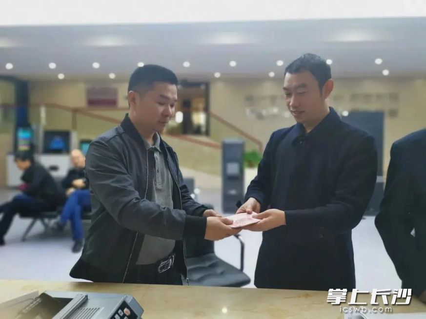 申请执行人接过执行法官手中的执行款。湖南高院供图