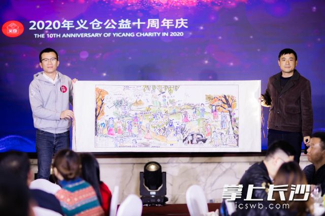 佘田桥二小校长申杰（右）将一幅由孩子们集体创作的画卷送给了义仓创始人赵世学（左）。受访者 供图