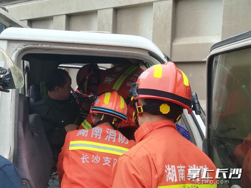 消防员对被困驾驶员展开救援。