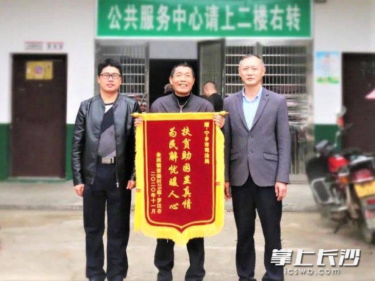 宁乡市箭楼村贫困户罗汉谷（中）制作了一面锦旗，送给一直关心他的宁乡市司法局帮扶干部。长沙晚报全媒体记者 张禹 通讯员 刘建兵 摄影报道