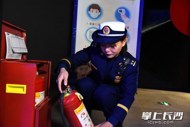 专项整治行动中，消防监督员检查商场灭火器。