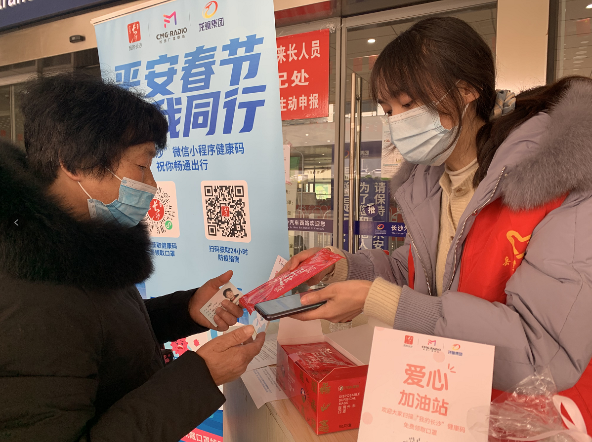 汽车西站，志愿者教乘客获取健康码，免费发放口罩。均为长沙晚报全媒体记者 邓艳红 摄