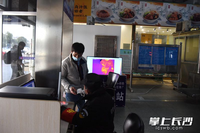 在长沙汽车东站，工作人员查验乘车人员身份信息并确认体温无异常后放行。