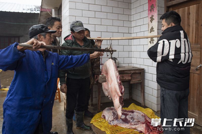 村民们帮忙给猪肉过称。长沙晚报全媒体记者 邹麟 摄