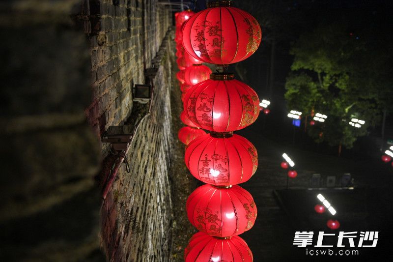 大红灯笼挂在古城墙前韵味十足。