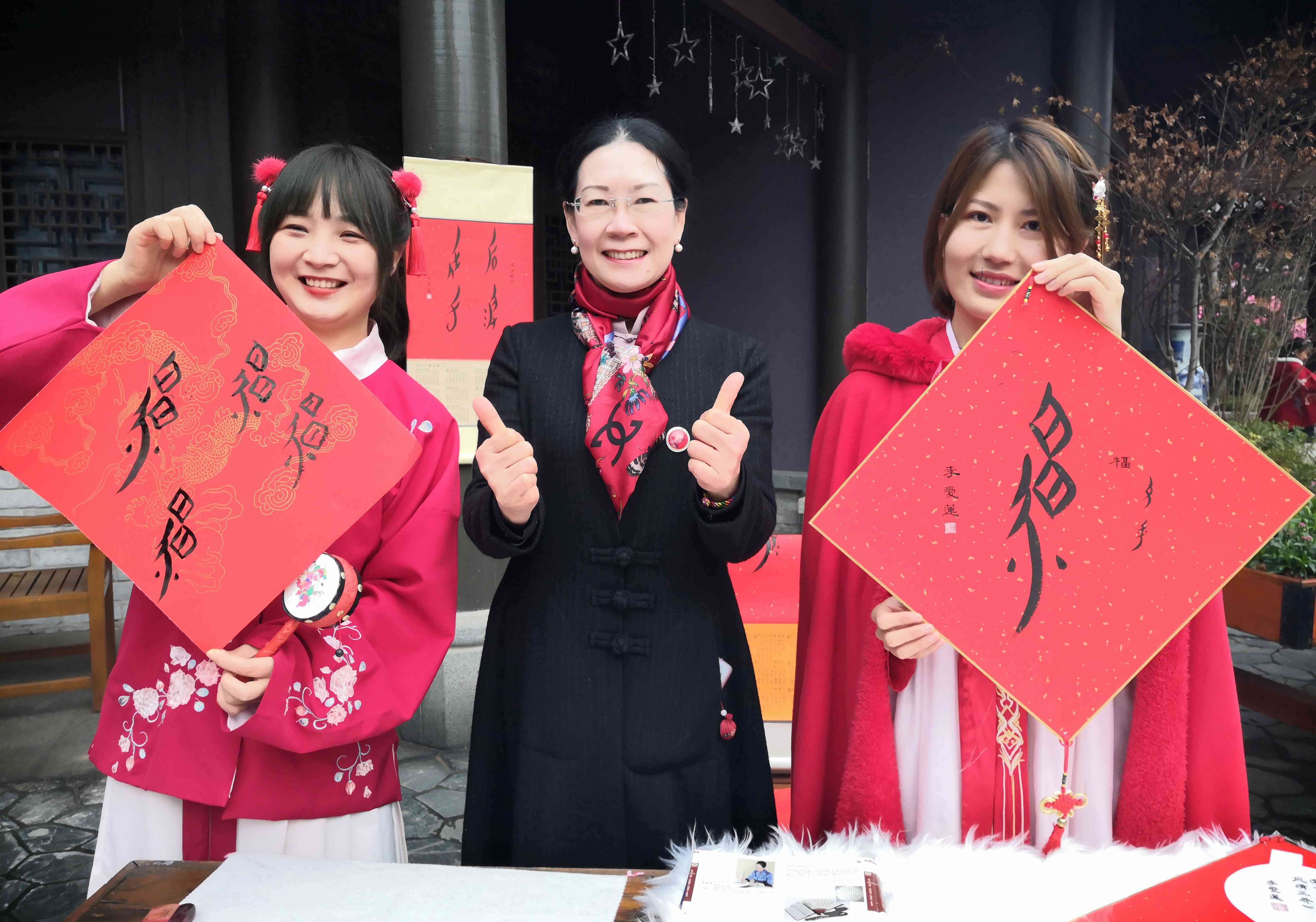 江永女书国家级传人何静华弟子李爱莲（中）给游客送女书“福”字。