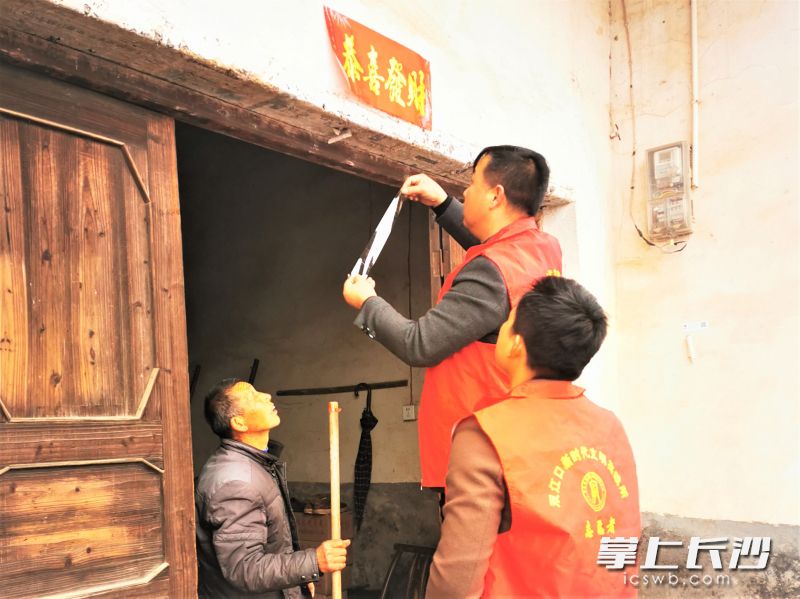 在走访慰问当中，双江口镇党员干部为乡亲家贴上春联。均为受访方供图