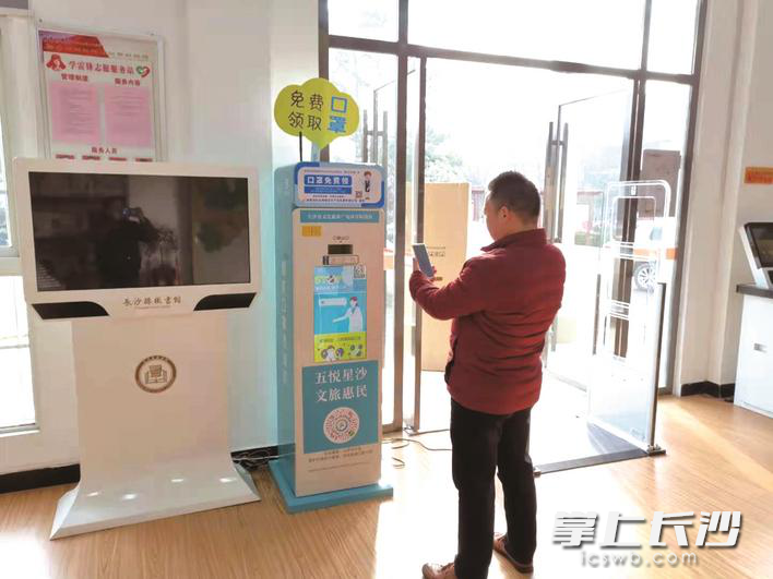 图为市民在扫码领取口罩。