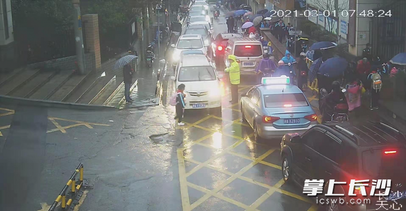 天心交警在学校门口冒雨疏导交通。