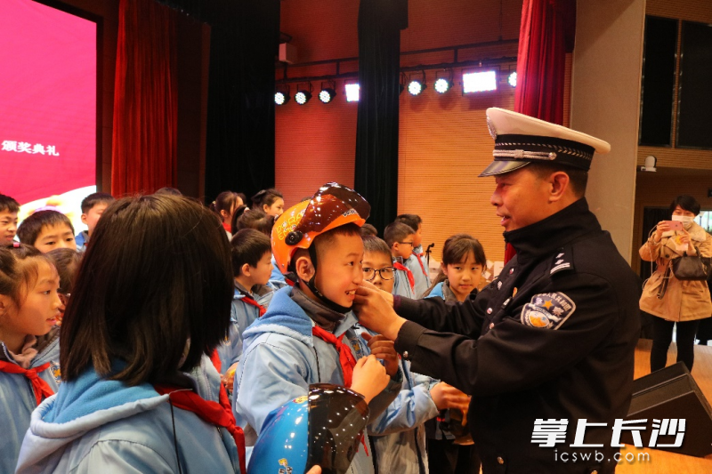 天心交警大队副大队长周正军为学生佩戴安全头盔。