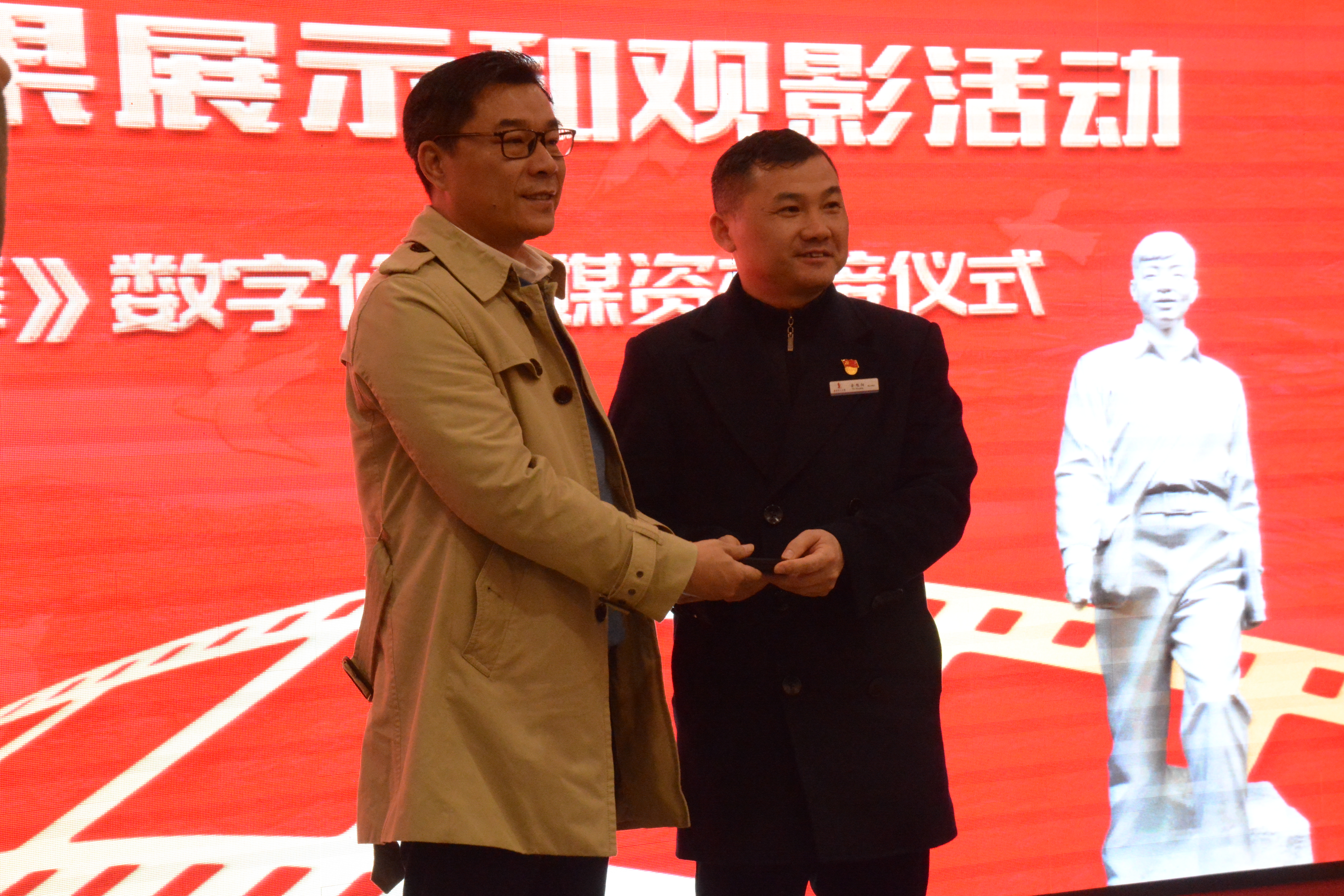 马栏山视频文创园管委会副主任胡朝晖与湖南雷锋纪念馆馆长余旭阳交接红色经典电影《雷锋》数字修复媒资。