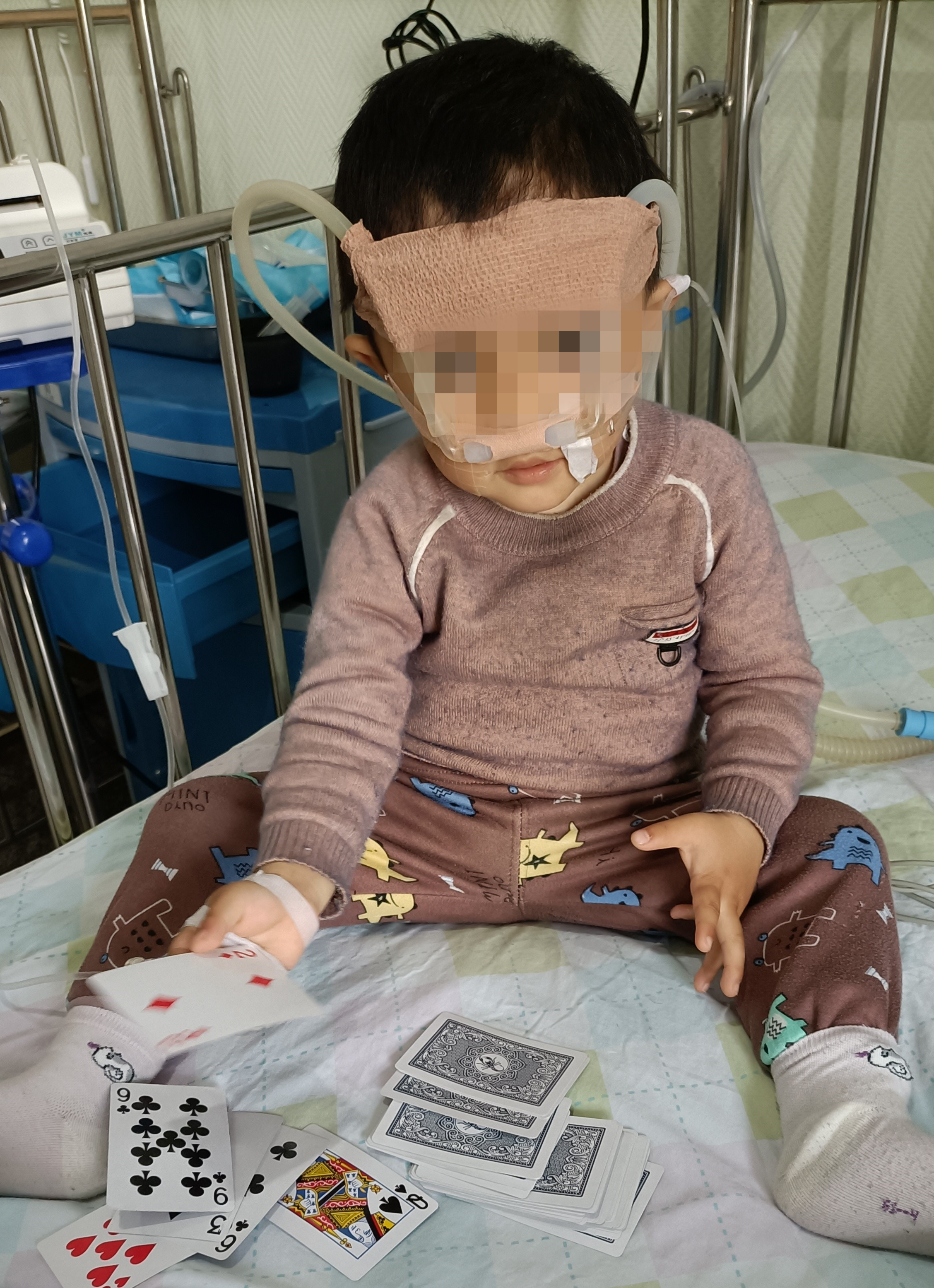 孩子情况稳定后，戴着无创呼吸机玩扑克。