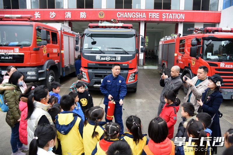 孩子们和家长向消防员认真学习灭火器的使用方法。