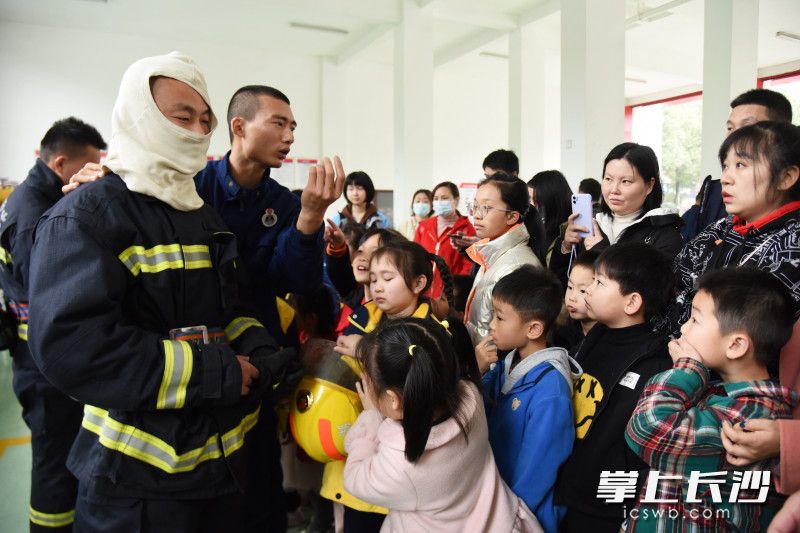 消防员向孩子们和家长介绍灭火战斗服。