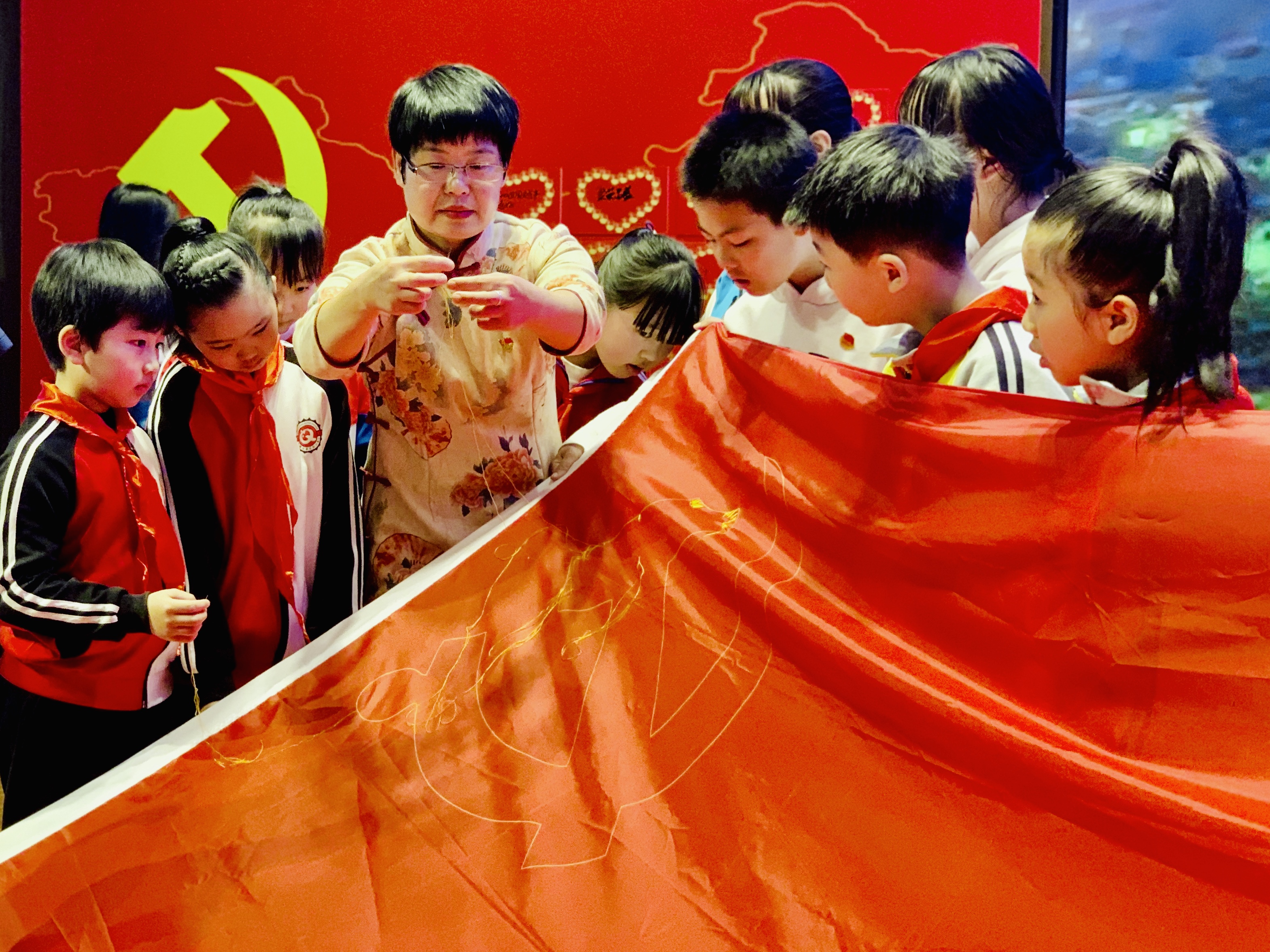 湘绣大师彭小花起针，现场教孩子们湘绣针法，众人接力绣党旗，庆祝党的生日。均为长沙晚报全媒体记者李卓摄
