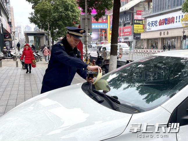 解放西路上，天心区城管执法人员对违停占用人行道的车辆进行处罚。长沙晚报全媒体记者 唐朝昭 摄