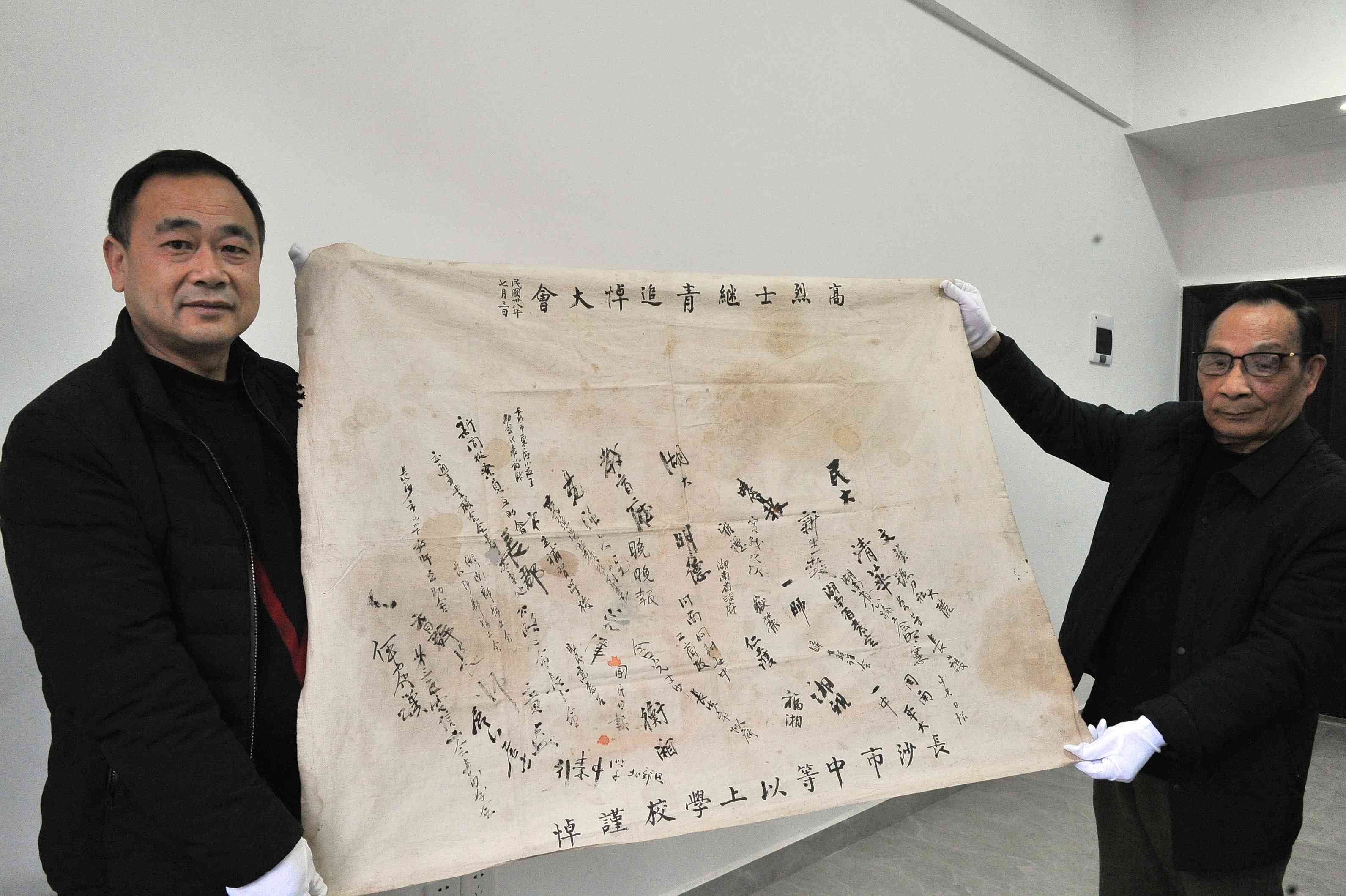 高继青烈士的胞弟高少青（右）日前向长沙党史馆捐赠高烈士继青追悼大会上长沙市中等以上学校签名物。
