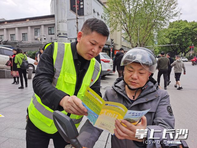 长沙市城市管理监督指挥中心党员向市民派发传单，宣传介绍长沙城管“市民随手拍”。