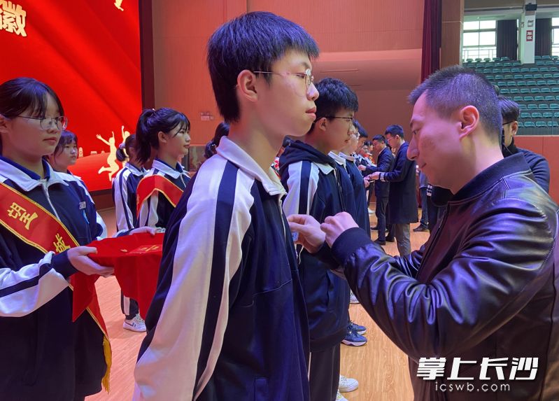 出席活动的嘉宾为新团员代表戴上团徽。