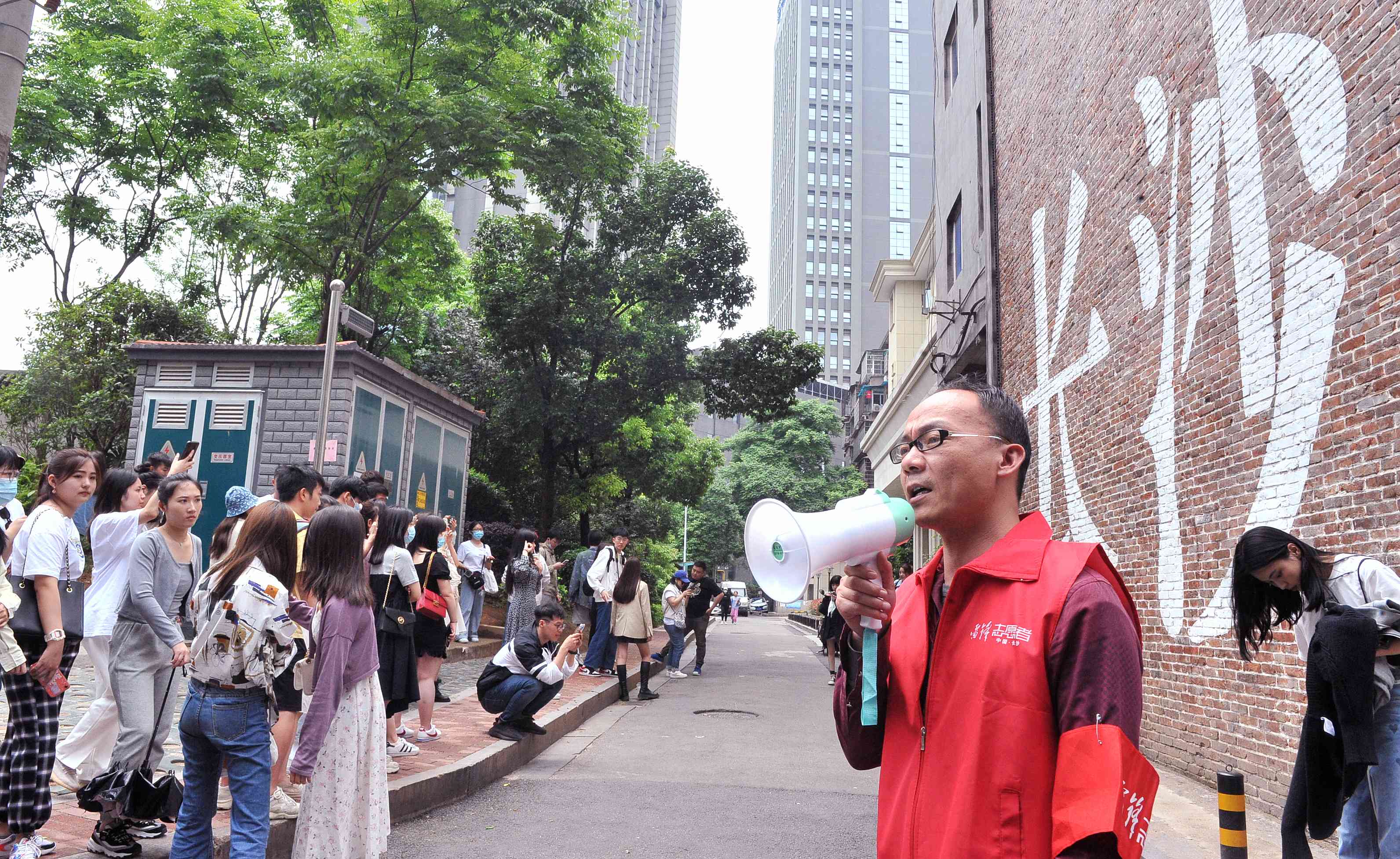 5日中午，胡美俐拿着小喇叭为游客解说米粉街和网红墙的来龙去脉，并为游客推荐长沙各个网红打卡点。长沙晚报全媒体记者 贺文兵 摄