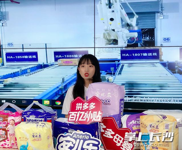 ▲ 直播间背后的大屏正在播放生产车间中机械手臂的作业情况。笑一|摄