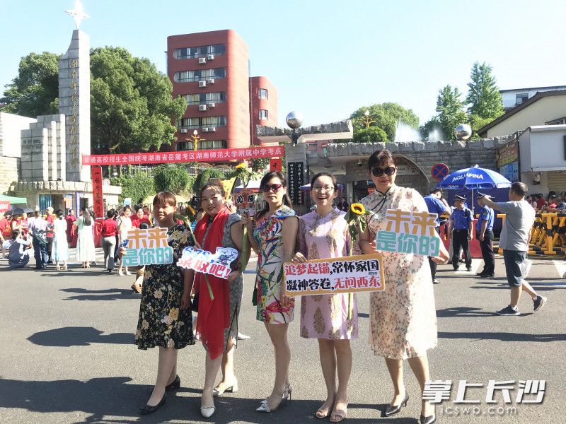 “旗袍妈妈”们手举向日葵和标语牌，祝考生“一举夺魁”。全媒体记者 刘俊 摄