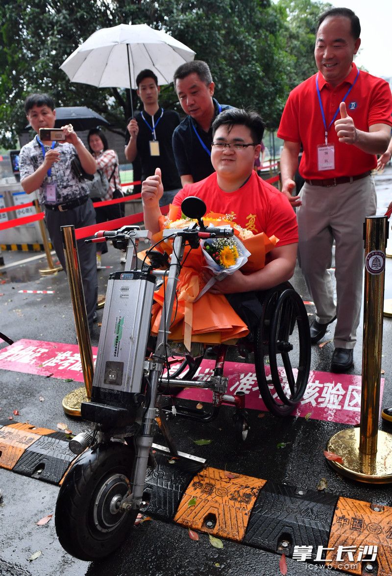 高考结束后，恒定中学校长蒋明权（右三）和执行董事李钊（右一）到考点门口接肖逸尘。长沙晚报全媒体记者 邹麟 摄