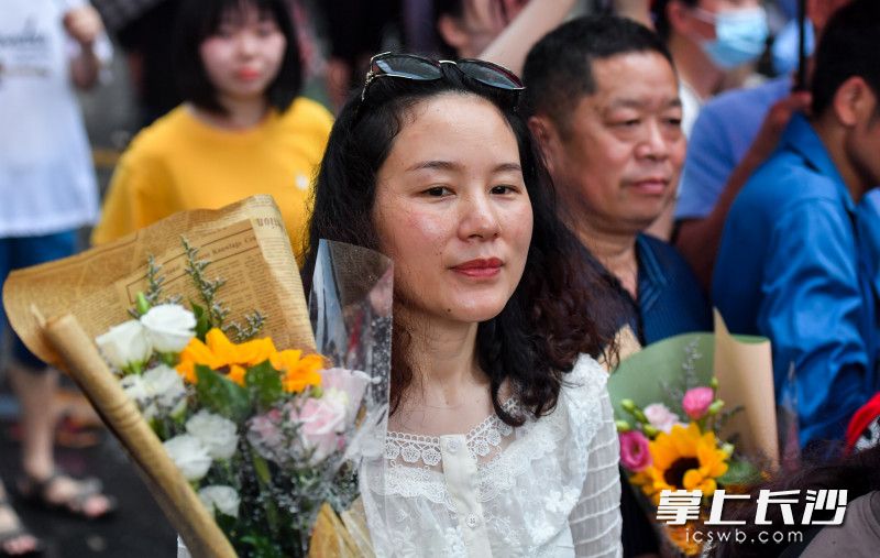 在长沙市实验中学考点外，一位家长抱着鲜花等待孩子出来。