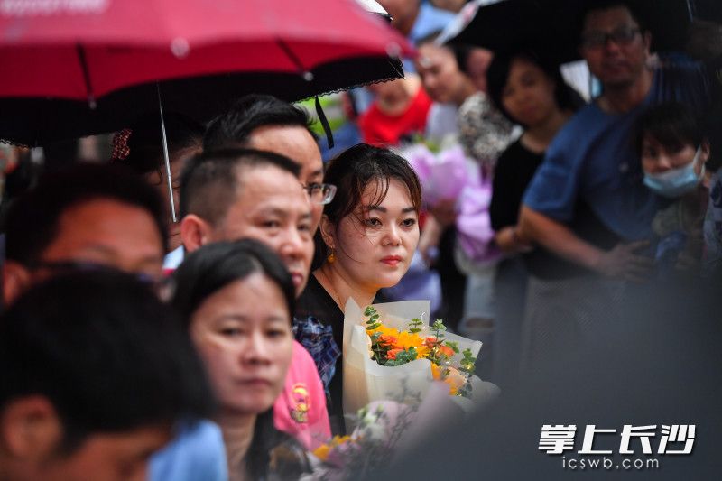 在长沙市实验中学考点外，一位家长抱着鲜花等待孩子出来。