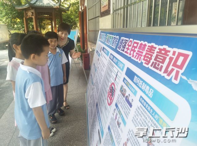 幼幼小学校长胡映和同学们一起观看禁毒知识展板。