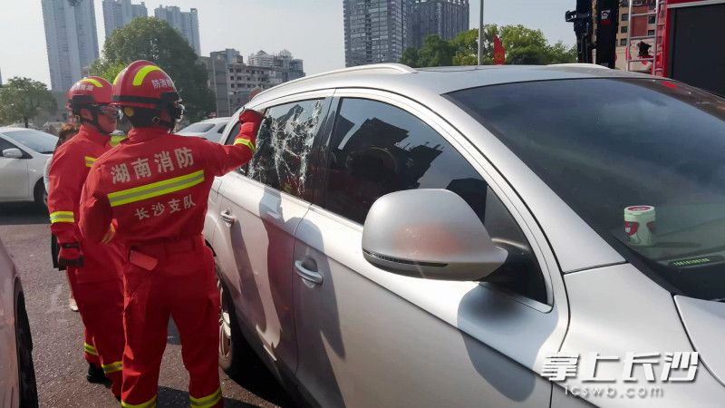 现场，消防员破拆车窗，进行救援。视频截图