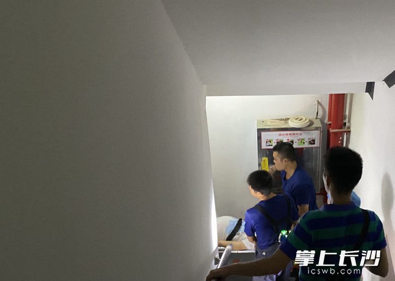 消防员小心翼翼，抬着担架一层一层走楼梯下楼。