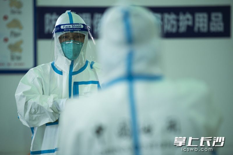 查验前，海关工作人员仔细地穿上防护服。