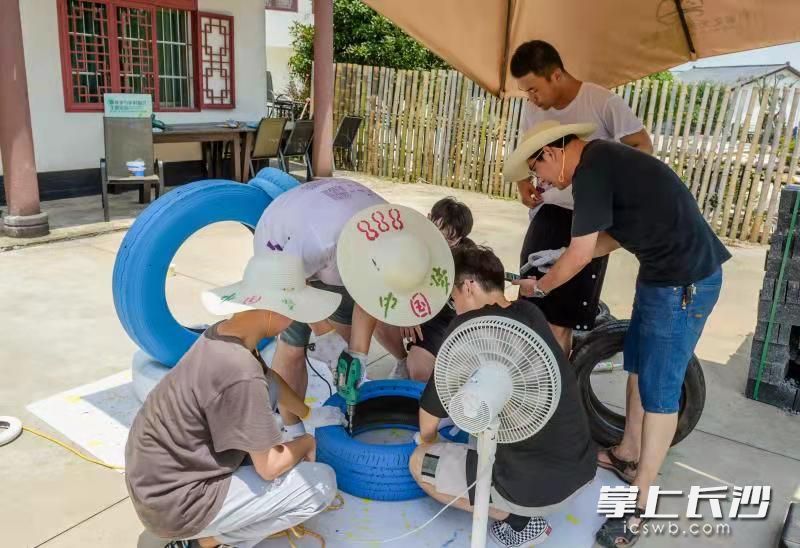 长沙理工大学设计艺术学院大二学生徐朝钢正在和几位同学切割轮胎。=