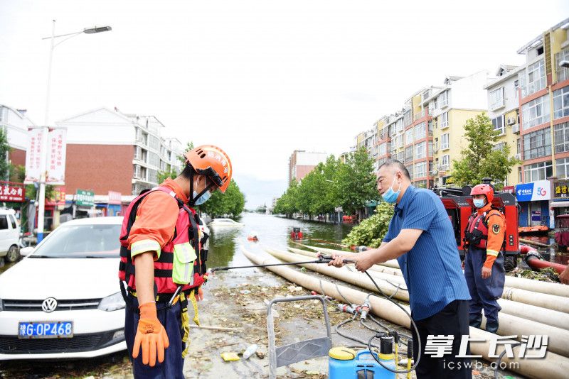 排涝现场，崔雯元为在积水中作业的消防员消毒。长沙晚报全媒体记者 刘琦 摄