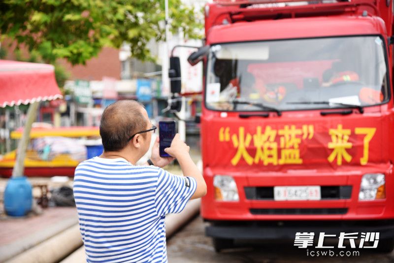 卫辉市民来到消防车前，拍照记录下长沙消防排涝瞬间。长沙晚报全媒体记者 刘琦 摄