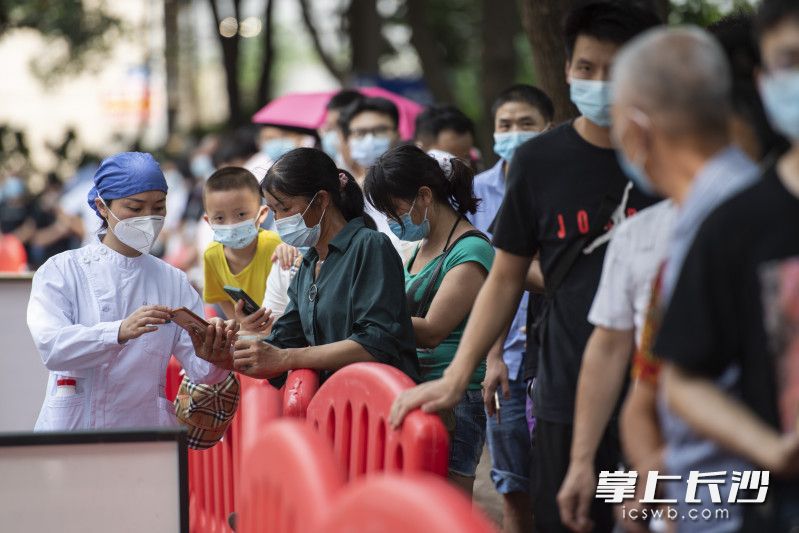 工作人员正在指导做核酸检测的市民进行手机登记。