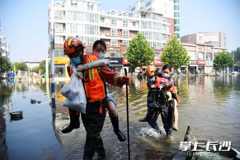 7月31日，在卫辉市人民路上，长沙消防员将两名女子从积水中背出。均为长沙晚报全媒体记者 刘琦 摄