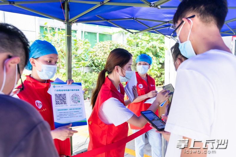 长沙市第一医院的志愿者在核酸检测采集点协助被检者。