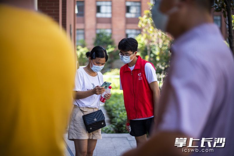 上午10点，在开福区一中核酸检测点，18岁的准大学生李红生在指导市民用手机进行核酸登记。