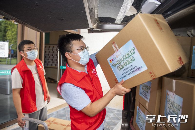 在长沙市青少年宫，志愿者们将爱心物资运装上车。