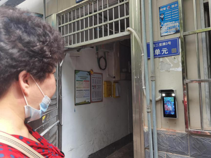 小区居民正在使用人脸识别门禁系统开门。
