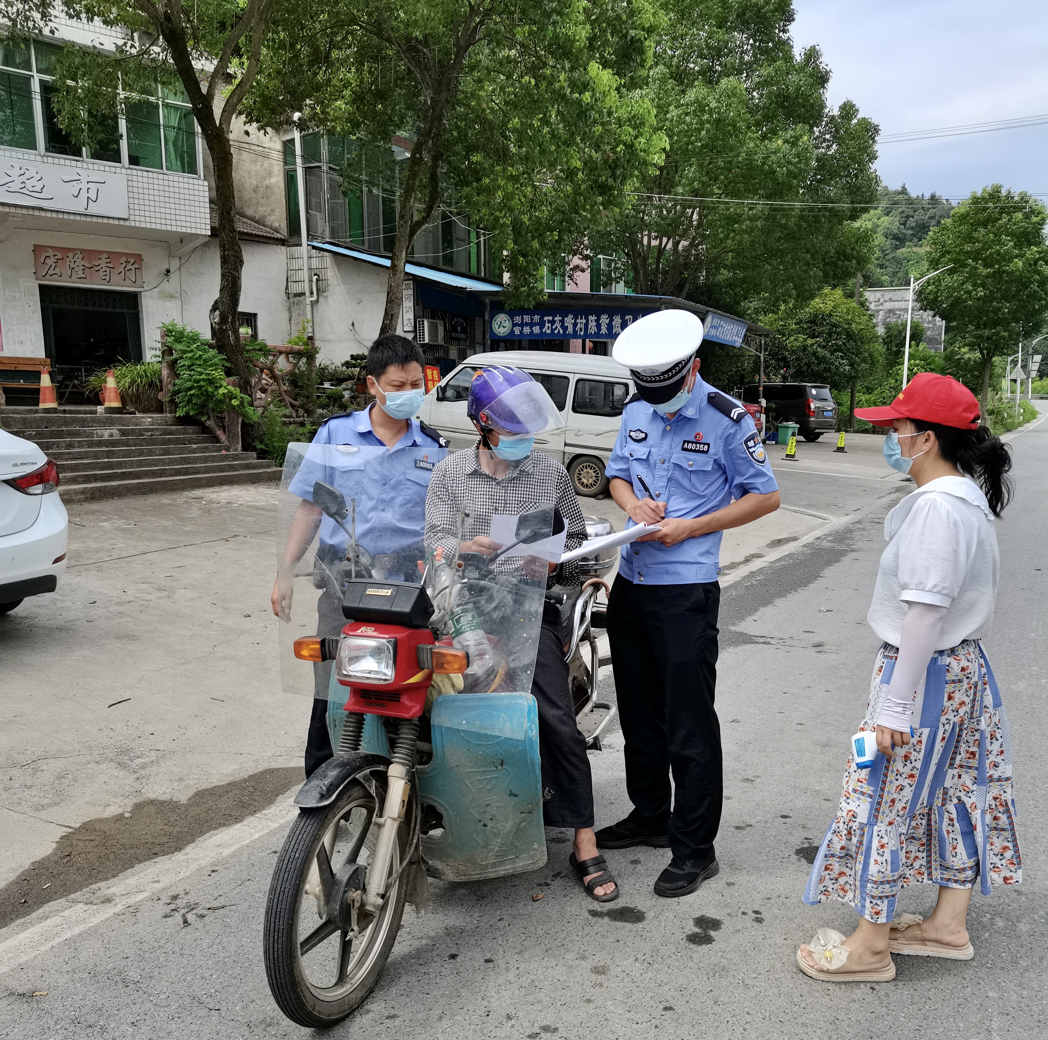 官桥镇交警、志愿者值守株木港，对过往人员进行“两码”查验、测量体温。  均为官桥镇政府供图