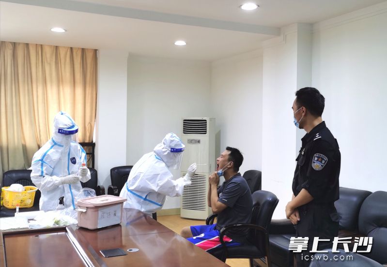 段旖亮（右）对接卫生防疫部门工作人员，协助开展对单位内部人员的核酸检测工作。
