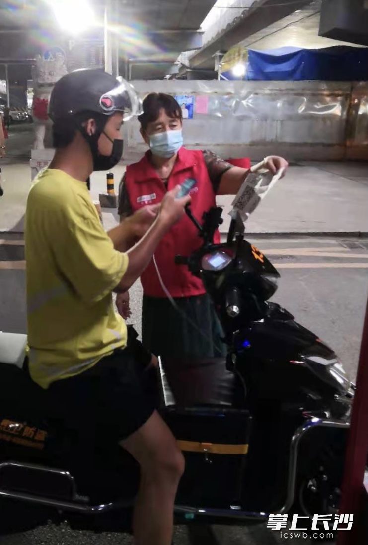 老党员志愿者在进出口提醒出入人员扫描并出示健康码。