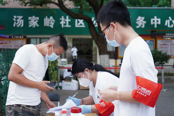 志愿者曾胤哲为居民测量体温。