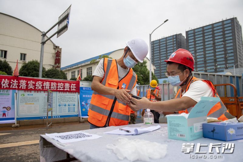 工人在查验健康码后进入施工场地。